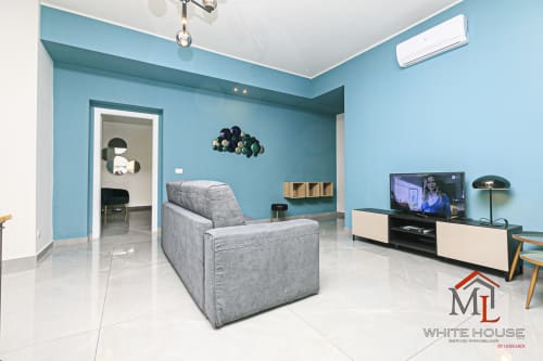 Moderno appartamento turchese nel Centro Storico di Genova con divano grigio, TV e arredi contemporanei