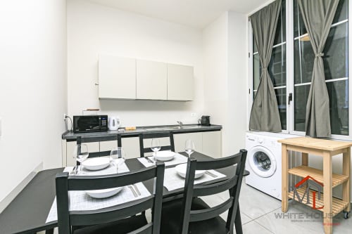 Cucina-sala da pranzo moderna negli Appartamenti Centro Storico di Genova, con sedie nere, elettrodomestici bianchi e vista sulla città