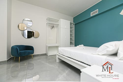Appartamento stile White House a Genova con camera moderna, parete azzurra, arredi bianchi e vista sulla città