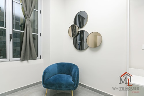 Poltrona blu con gambe dorate nell'appartamento ML White House di Genova, con specchi decorativi e vista sulla città