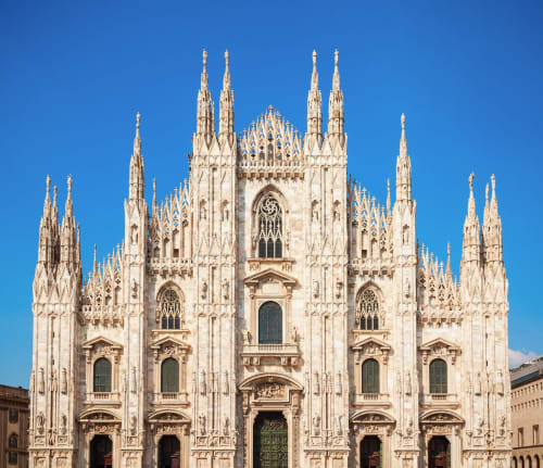 Maestosa cattedrale gotica in marmo bianco con guglie contro il cielo azzurro a Milano, Italia