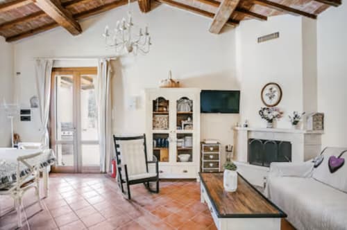 Casa Rossi Roma living room with exposed wooden beams, fireplace, white shelving, and terracotta tile flooring