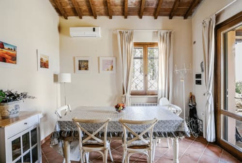 Tuscan-style dining room at Casa Rossi Roma with wooden beamed ceiling, cream walls, and natural light from terracotta
