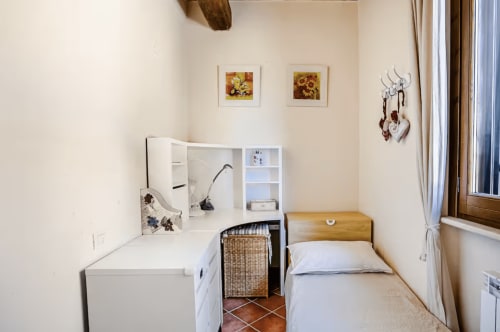 Cozy single bedroom at Casa Rossi Roma with desk, wicker chair, and window overlooking Rome