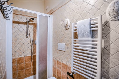 Modern bathroom at Casa Rossi Roma with walk-in shower, heated towel rack, and beige tile walls