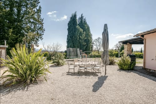 Casa Rossi Roma outdoor patio with dining table, umbrella, and Mediterranean landscaping