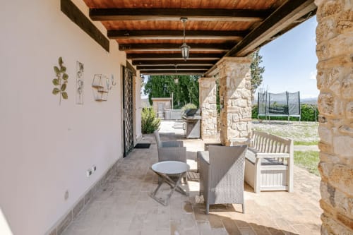 Covered patio with stone pillars, wooden beams, comfortable seating and views at Casa Rossi Roma