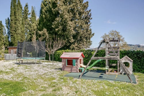 Casa Rossi Roma children's play area with trampoline, log cabin, and wooden playground equipment in rural Italian garden