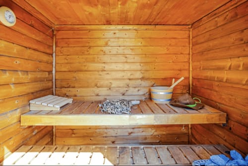Traditional wooden sauna interior at Casa Rossi Roma with bench, bucket, and accessories