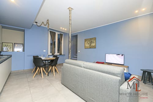 Moderno appartamento nel Centro Storico di Genova con living open-plan, divano grigio, zona pranzo e cucina con pareti blu