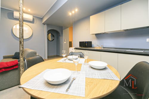 Moderna zona pranzo dell'appartamento genovese con tavolo tondo in legno, cucina e vista sulla città