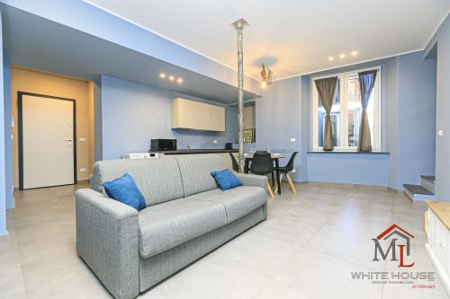 Moderno appartamento a Genova con divano grigio, angolo cottura e vista sulla città presso ML White House