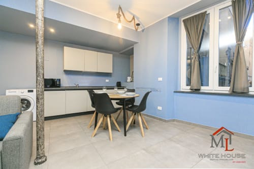 Cucina-sala da pranzo moderna nell'appartamento ML White House Genova con pareti blu, mobili bianchi e vista sulla città