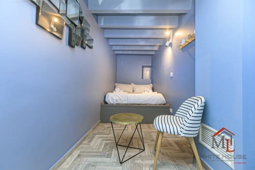 Camera da letto moderna nell'appartamento ML White House a Genova Centro Storico, con letto, sedia rigata e pavimento a spina di pesce