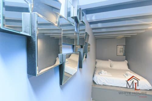 Camera da letto moderna nella ML White House a Genova con parete specchiata, letto queen, travi in legno e vista sulla città