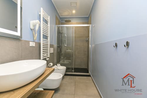 Bagno moderno nell'appartamento ML White House Genova con lavandino d'appoggio, doccia, wc e scaldasalviette elettrico