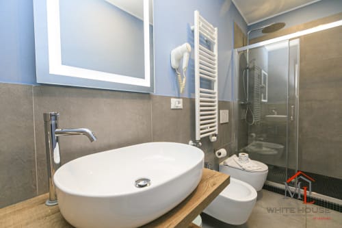 Bagno moderno presso l'appartamento ML White House a Genova con lavabo bianco, doccia a pioggia, scaldasalviette e illuminazione LED