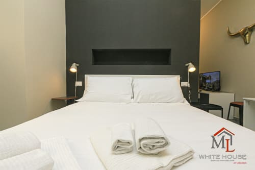 Camera da letto moderna con biancheria bianca e asciugamani arrotolati negli appartamenti ML White House nel Centro Storico di Genova