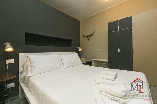 Camera da letto moderna della ML White House a Genova con biancheria bianca, testata scura e vista sulla città