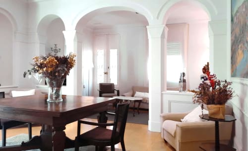 Elegante comedor del Hotel Can Carol con columnas arqueadas, mesa de madera oscura y arreglos florales secos en Capellades