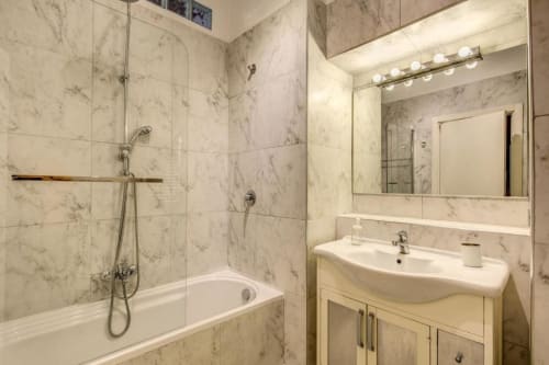 Bagno in marmo moderno dell'appartamento Downtown Srl Roma con doccia, vasca, lavabo e specchio grande con illuminazione