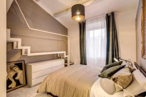 Camera da letto moderna nell'appartamento Downtown Srl a Roma, con letto, scaffalatura geometrica a parete, lampada a sospensione e vista sulla corte interna.