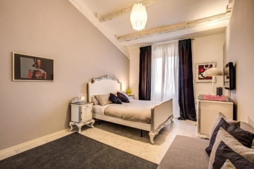 Camera da letto elegante nell'appartamento The Great Pop a Roma con letto ornato, tende nere, arredi moderni e corte interna