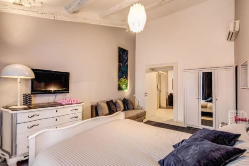 Camera da letto moderna a Roma con letto queen, mobili bianchi, camino e area soggiorno con vista sulla città