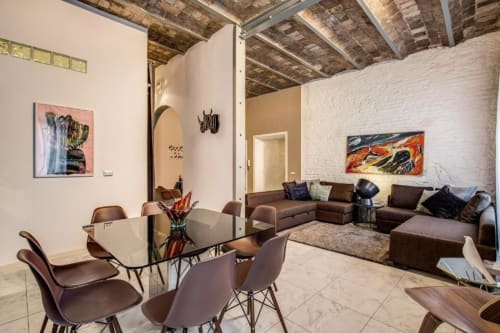 Moderna zona living a Roma con divano in pelle marrone, tavolo da pranzo, soffitto in mattoni a vista e design contemporaneo