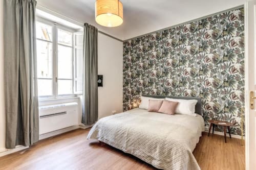 Camera da letto presso Downtown Srl Roma con carta da parati floreale, letto matrimoniale, finestra con vista giardino, pavimenti in legno e servizi moderni.