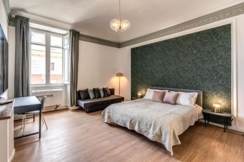 Spaziosa camera da letto a Roma con parete verde, letto queen, divano, scrivania e vista giardino