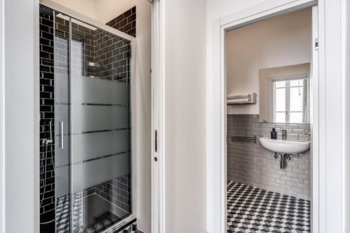 Bagno moderno in appartamento romano con piastrelle nere a subway, box doccia in vetro satinato e pavimento a scacchiera bianco e nero