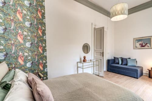 Camera da letto nell'appartamento The Great Green a Roma con carta da parati floreale, divano letto e vista sul giardino