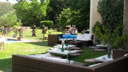 Jardín de descanso del Hotel Can Carol con muebles de mimbre, césped y muros cubiertos de hiedra en Capellades