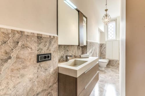 Bagno moderno con rivestimento in marmo, vanity bianca, specchio e WC nell'appartamento di Emily a Roma