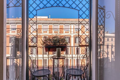 Vista dal balcone degli edifici storici arancioni di Roma con ringhiere in ferro battuto e piante in vaso all'appartamento Emily
