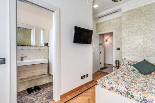 Camera da letto della casa di Emily a Roma con bagno ensuite, biancheria floreale e vista sulla città