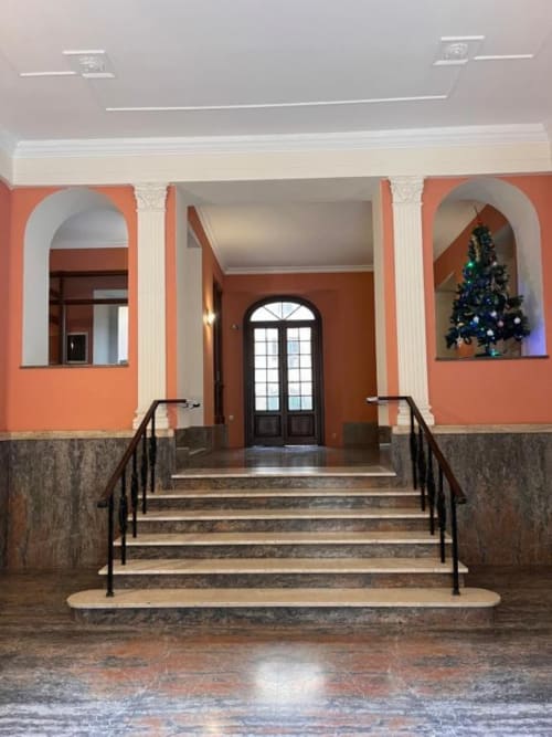 Elegante ingresso di appartamento romano con pareti arancioni, colonne classiche e albero di Natale decorato
