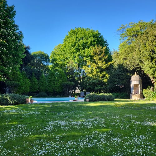 Jardin luxuriant avec piscine bleue au Logis des Tourelles B&B à Cognac, entouré d'arbres matures et de fleurs sauvages