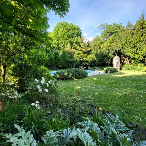 Jardin luxuriant du Logis des Tourelles avec piscine, pelouse soignée et arbustes fleuris à Cognac