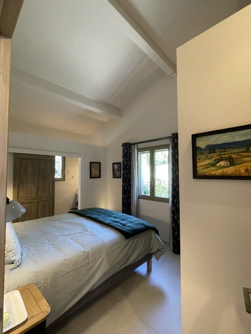 Helles Schlafzimmer mit Queensize-Bett, Schrägdach und Glastüren mit Blick auf die Landschaft von Gordes im SARL MARIEMEO