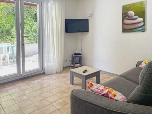 Séjour moderne avec canapé gris, TV et accès à la terrasse - appartement LOCADIGNE à Digne-les-Bains