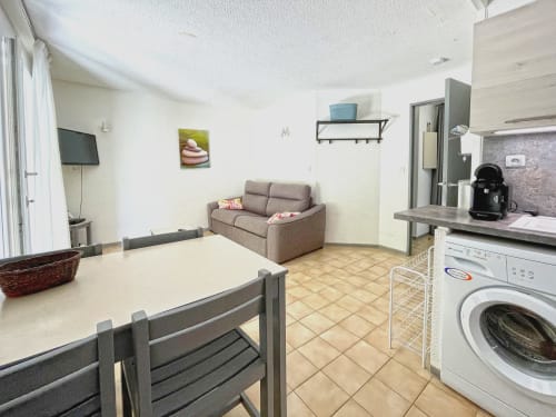 Cuisine ouverte et salon avec table à manger, canapé, lave-linge et électroménagers modernes chez LOCADIGNE