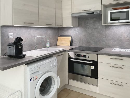 Cuisine moderne de l'appartement LOCADIGNE avec lave-linge, four encastré, évier et plan de travail gris, Digne-les-Bains