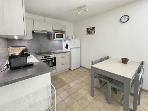 Cuisine et salle à manger modernes de l'appartement Vallon des Sources à Digne-les-Bains, avec mobilier blanc, table