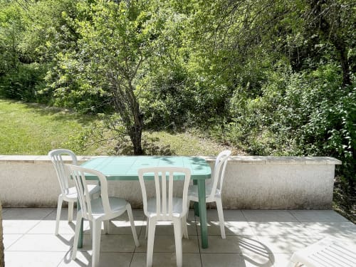 Terrasse de jardin du pavillon LOCADIGNE avec table à manger, chaises et vue ombragée par les arbres à Digne-les-Bains