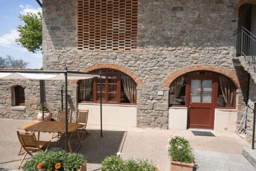 Appartamento nel portico di Villa Olena a Reggello con archi in pietra, porte rosse e vista sulle montagne