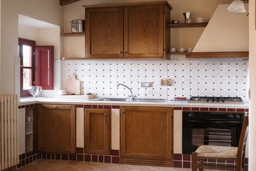 Cucina dell'appartamento Villa Olena Lischeto con mobili in legno, schienale in pegboard bianco e fornello a gas nero a Reggello