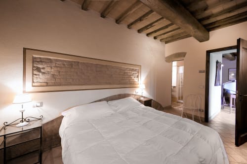Camera da letto Roncaticcio a Villa Olena, Reggello, con biancheria bianca, travi in legno e accesso alla vista giardino