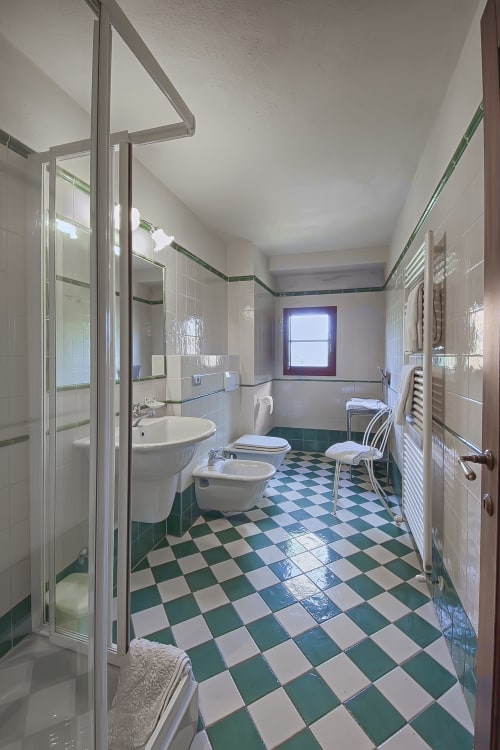 Bagno spazioso di Villa Olena a Reggello con pavimento a quadretti verde e bianco, doccia, lavabo e WC